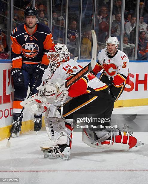 Goalie Miikka Kiprusoff of the Calgary Flames skates behind his net and uses both hands to backhand the puck clear of Trent Hunter of the New York...