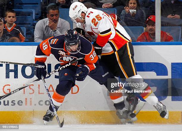 Jack Hillen of the New York Islanders and David Moss of the Calgary Flames battle for the puck during an NHL game at the Nassau Coliseum on March 25,...