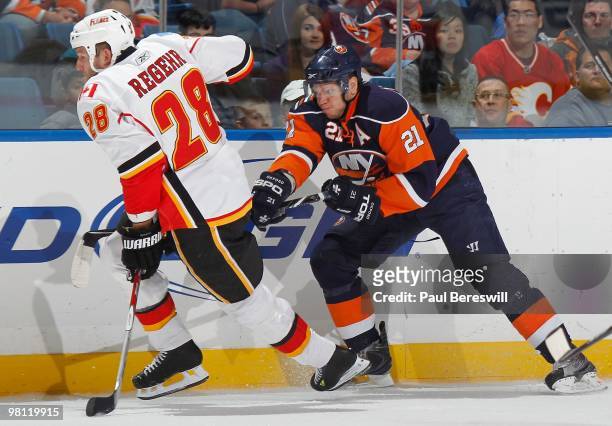 Robyn Regehr of the Calgary Flames skates away fast as Kyle Okposo of the New York Islanders tries to slow him down during an NHL game at the Nassau...