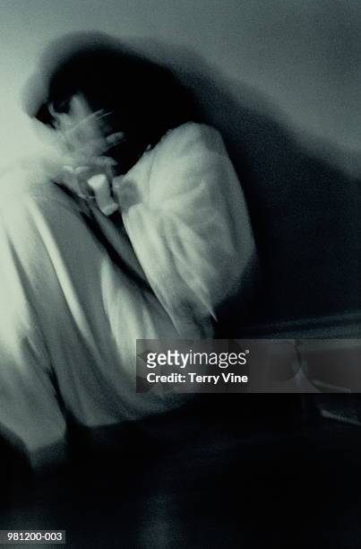 woman curled on floor shielding herself with hands, blurred (b&w) - victim stock-fotos und bilder