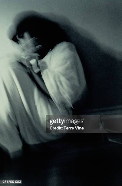 woman curled on floor shielding herself with hands, blurred (b&w) - violenza foto e immagini stock