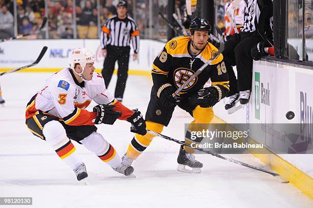 Marco Sturm of the Boston Bruins watches the loose puck against Ian White of the Calgary Flames at the TD Garden on March 27, 2010 in Boston,...