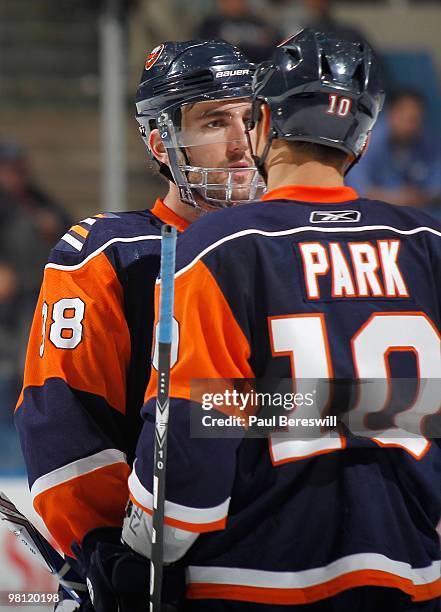 Jack Hillen talks with teammate Richard Park of the New York Islanders during a timeout against the Calgary Flames during an NHL game at the Nassau...