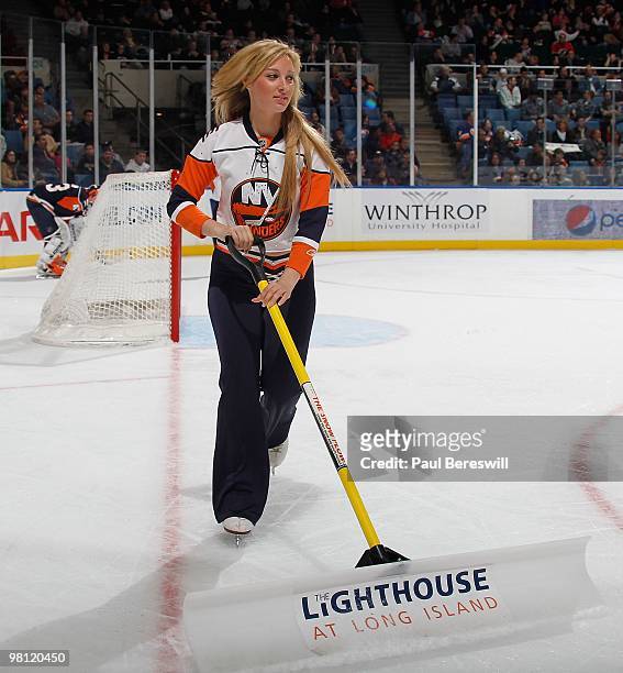 An Islanders ice girl scrapes the ice during a timeout at an NHL game between the Calgary Flames and the New York Islanders at the Nassau Coliseum on...