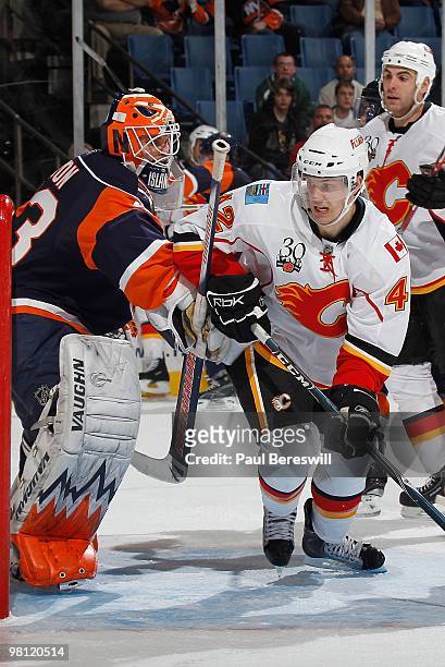 Center Brett Sutter of the Calgary Flames is checked by the stick of goalie Martin Biron of the New York Islanders during an NHL game at the Nassau...