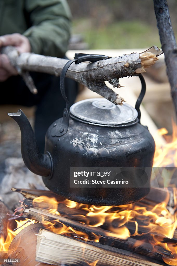 Man Holding Tea Kettle Over Campfire With Stick High-Res Stock Photo -  Getty Images