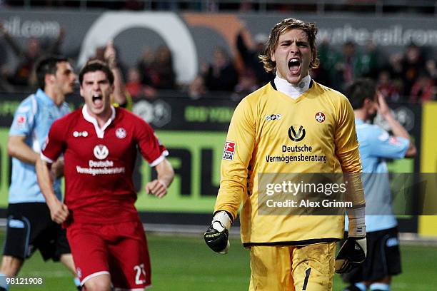 Goalkeeper Tobias Sippel of Kaiserslautern celebrates with team mate Florian Dick after parrying a penalty by Alexander Ludwig of Muenchen during the...