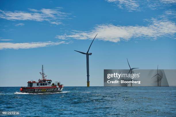Boat passes wind turbines on the EDF Blyth Offshore Demonstrator wind farm, operated by EDF Energy Renewables Ltd., off the Northumberland coast in...