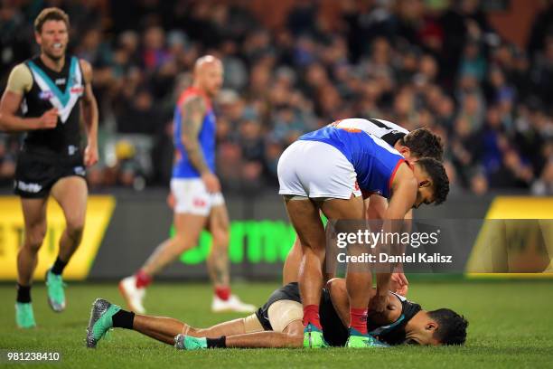 Lindsay Thomas of the Power is attended to by Neville Jetta of the Demons during the round 14 AFL match between the Port Adelaide Power and the...