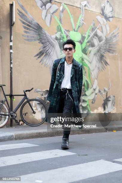 Guest is seen on the street during Paris Men's Fashion Week S/S 2019 wearing a black and green design long coat with white shirt and black pants on...