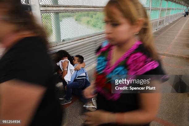 Crying Honduran woman and her child wait along the border bridge after being denied into the Texas city of Brownsville which has become dependent on...