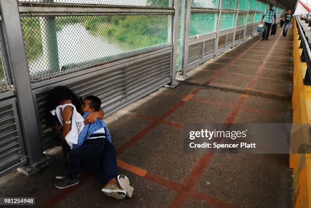 Crying Honduran woman and her child wait along the border bridge after being denied into the Texas city of Brownsville which has become dependent on...