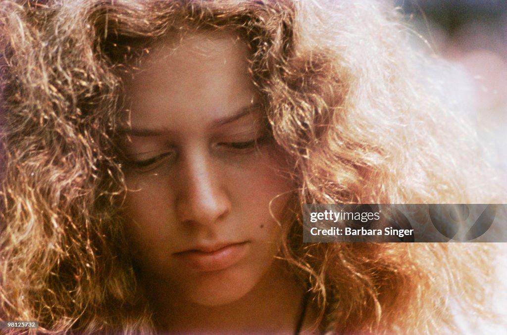 Teenage girl with curly hair looking down