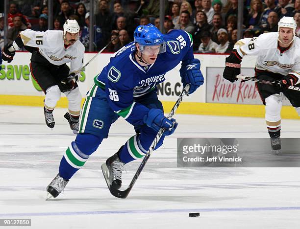George Parros and Kyle Chipchura of the Anaheim Ducks look on as Jannik Hansen of the Vancouver Canucks skates up ice with the puck during their game...