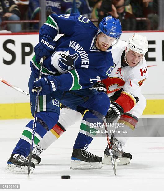 Daniel Sedin of the Vancouver Canucks and Jay Bouwmeester of the Calgary Flames battle for the puck during their game at General Motors Place on...
