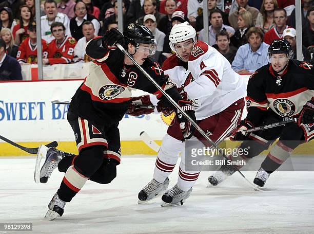 Jonathan Toews of the Chicago Blackhawks charges past Zbynek Michalek of the Phoenix Coyotes, as Troy Brouwer of the Blackhawks waits in position...