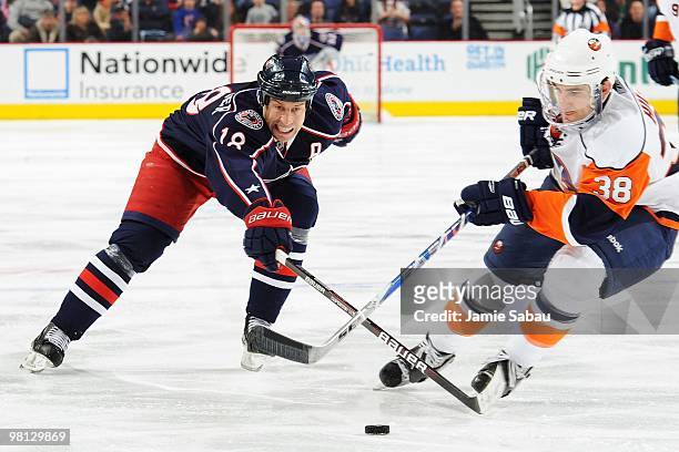 Forward R.J. Umberger of the Columbus Blue Jackets attempts to poke the puck away from Defenseman Jack Hillen of the New York Islanders on March 27,...