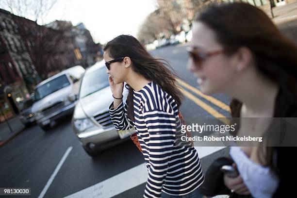 Young woman speaks on a cell phone while crossing a four-lane avenue March 19, 2010 in Brooklyn, New York. 57% of teens surveyed feel cell phones are...