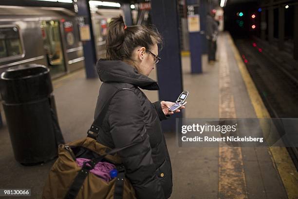 Young woman writes a text message on a cell phone while waiting for a subway train March 24, 2010 in New York. 2.5 billion text messages are sent...