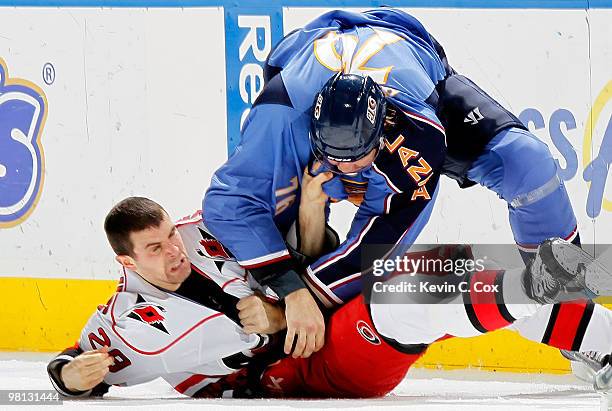 Evgeny Artyukhin of the Atlanta Thrashers knocks down Tom Kostopoulos of the Carolina Hurricanes at Philips Arena on March 29, 2010 in Atlanta,...