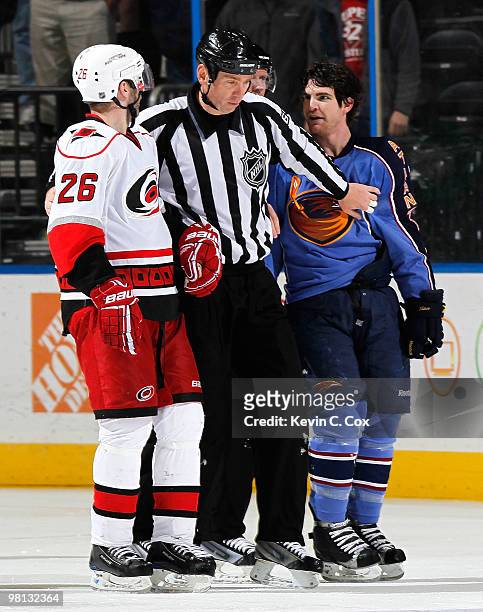 Linesman Pierre Racicot stands between Erik Cole of the Carolina Hurricanes and Jim Slater of the Atlanta Thrashers as he escorts them to their...