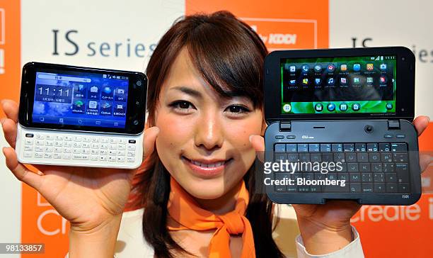 Model displays KDDI Corp.'s Sharp Corp. Manufactured IS01 smartphone, right, running Google Inc.'s Android operating system, and a Toshiba Corp....