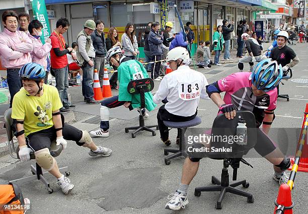 Participants riding office chairs run during the Kirara 2 Hours ISU Endurance Race at Kirara Shopping Street on March 28, 2010 in Kyotanabe, Kyoto,...