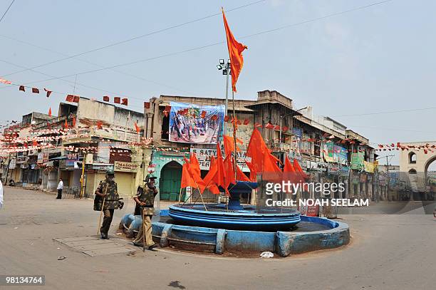 Indian police walk past a fountain decorated with orange flags for the Hindu Lord Hanuman Jayanthi festival during an indefinite curfew imposed on...