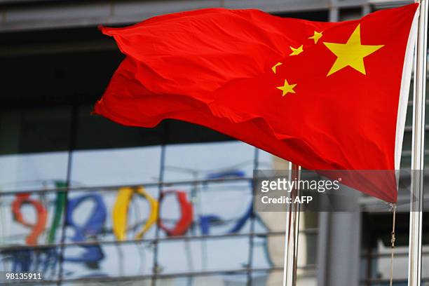 The Google logo is reflected in windows of the company's China head office as the Chinese national flag flies in the wind in Beijing on March 23,...