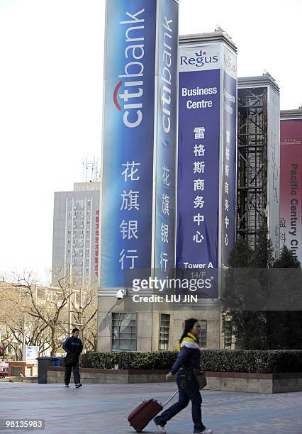 People walk near billboards in Beijing on March 25, 2010. Thirty years after Beijing opened up to foreign investment, international companies face...