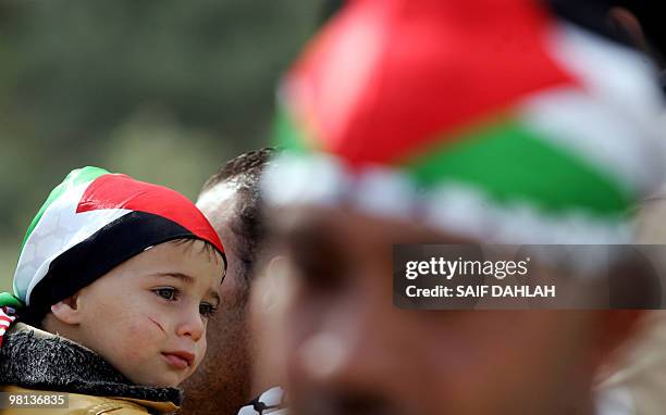 Palestinian man carries his son wearing his national flag on his head during a demonstration marking Land Day in the village of Zabda in the northern...