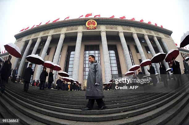 Ushers with umbrellas wait for the arrival of delegates to the closing session of the annual National People's Congress at the Great Hall of the...