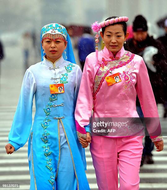 Two delegates in traditional costumes arrive for the closing session of the annual National People's Congress at the Great Hall of the People in...