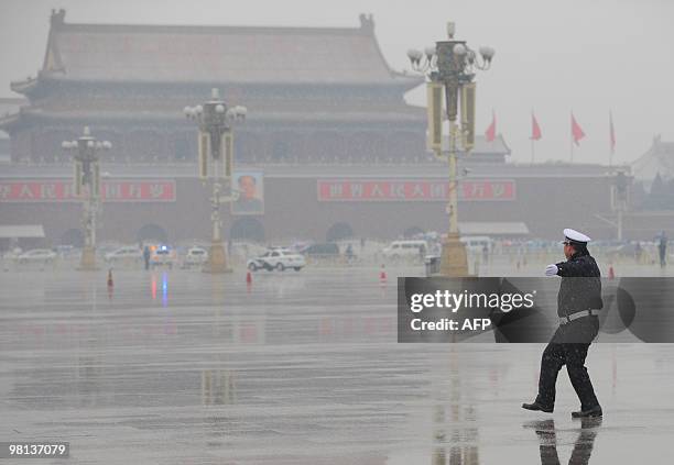 Policeman prepares to guide the buses bringing delegates to the closing session of the annual National People's Congress at the Great Hall of the...