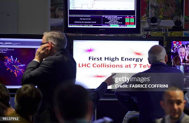 European Organization for Nuclear Research scientists react after the first ultra high-energy collisions at the CMS experiment control room on March...