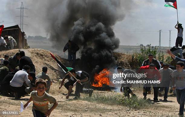 Palestinian youths take cover as they clash with Israeli soldiers at the border fence near Gaza City on March 30, 2010 to protest in the occasion of...