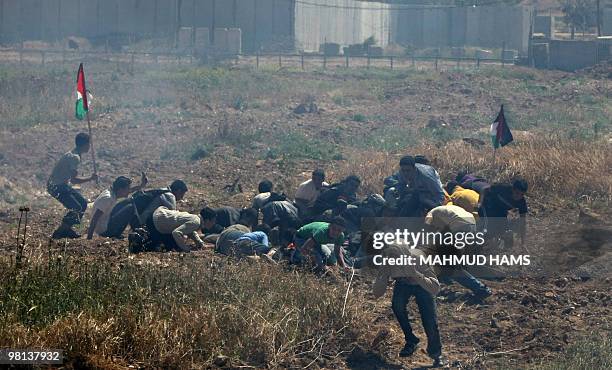 Palestinian youths take cover as they clash with Israeli soldiers at the border fence near Gaza City on March 30, 2010 to protest in the occasion of...