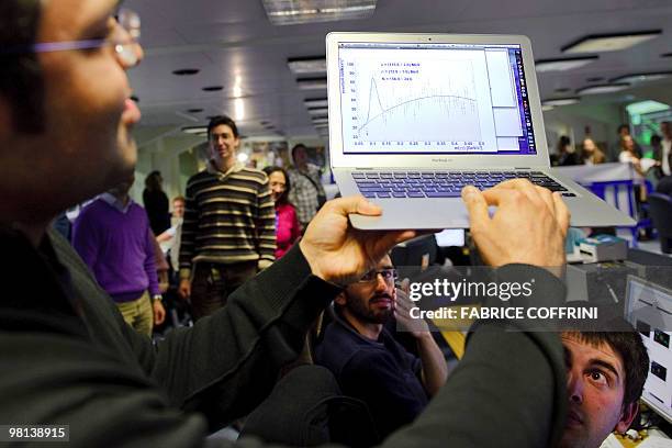 An European Organization for Nuclear Research scientist shows on his laptop the first results of the first ultra high-energy collisions at the CMS...