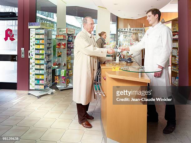 70 years old male paying in pharmacy - 30 34 years stock-fotos und bilder