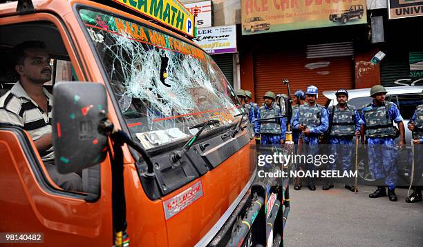 Indian Rapid Action Force personnel look on, as a driver manouvers a van damaged during an outbreak of communal violence past them, at Nalla Gutta in...