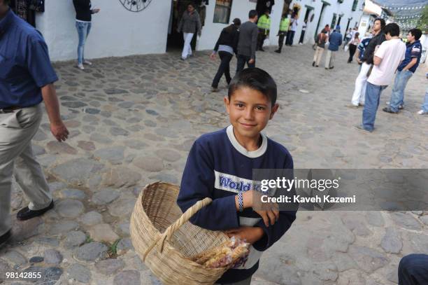 Street vendor boy wearing a tee-shirt with 'World Kids' printed on it sells nuts in a basket near Plaza Mayor. Villa de Leyva is a colonial town and...