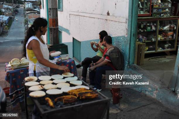 Young couple buy Arepa from a street vendor on the main street in the city center. An arepa is a bread made of corn popular in both Colombia and...