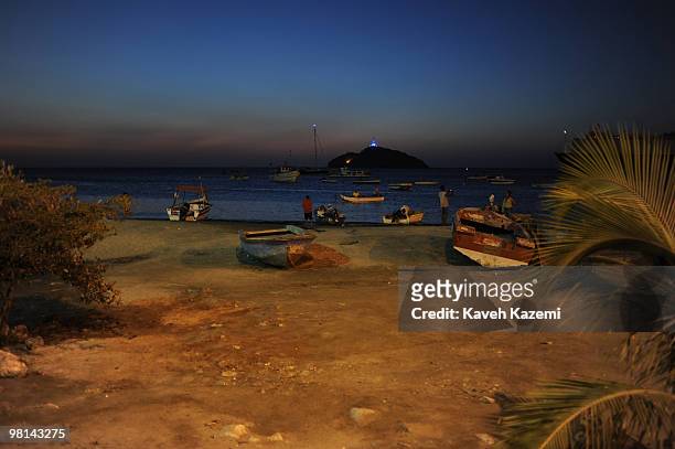 View of beach front at night with fishing boats at shore and boats anchored near the shore. Santa Marta is a city and municipality located in...