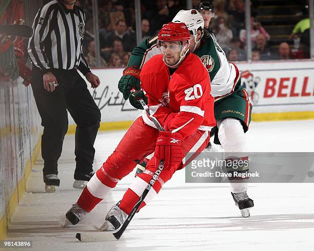 Drew Miller of the Detroit Red Wings protects the puck from James Sheppard of the Minnesota Wild during an NHL game at Joe Louis Arena on March 26,...