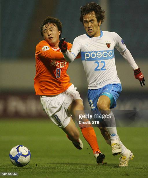 China's Shandong Luneng FC's Wang Yongpo challenges for the ball with South Korea's Pohang Steelers' No Byung Jun during the AFC Champions League...