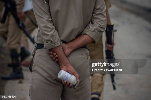 An Indian policeman holds a teargas canister before hurling them at Kashmir protesters during a protest on June 22, 2018 in Srinagar, the summer...