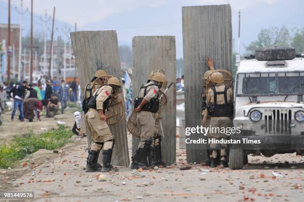 Police take guard behind a barricade as Kashmiri protesters clashed with police after forces killed four militants on June 22, 2018 in the outskirts...