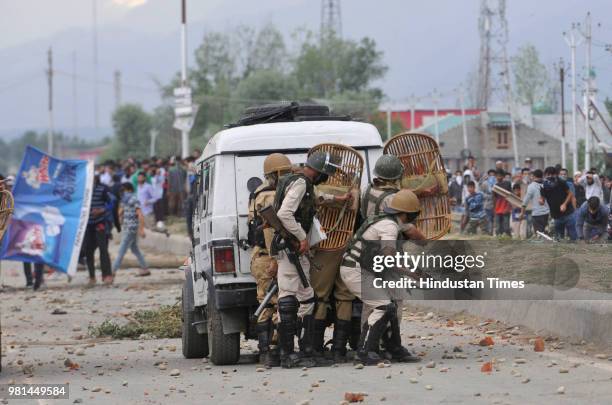 Police take guard behind a vehicle as Kashmiri protesters clashed with police after forces killed four militants on June 22, 2018 in the outskirts of...