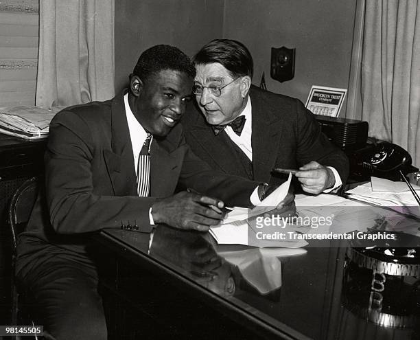 Jackie Robinson, left, and Branch Rickey share a joke during a contract signing session in the front offices of the Brooklyn Dodgers at Ebbets Field...