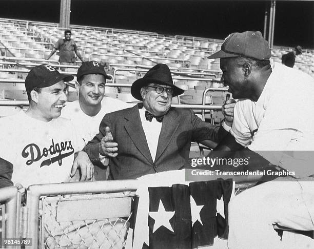 Jackie Robinson has just been hit in the head with a pitch and is being helped by the Brooklyn Dodgers trainer and third base coach, in a game during...